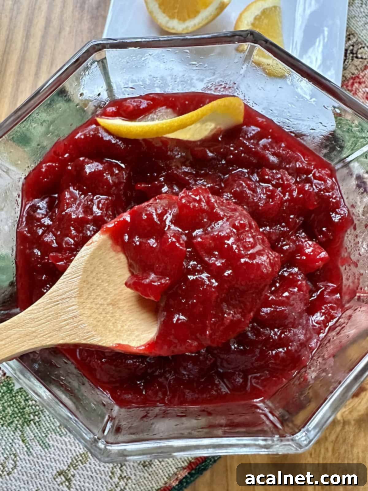 Cranberry orange sauce in a bowl with a spoon and a slice of orange.