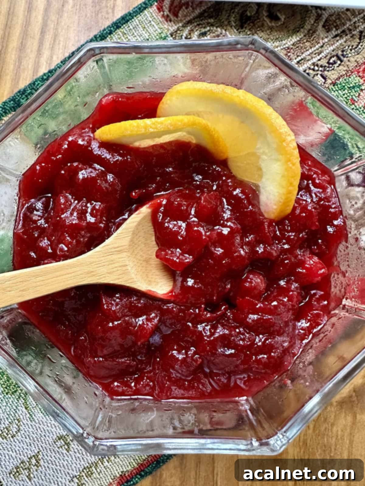 Two slices of orange in a bowl of cranberry orange sauce with a spoon.
