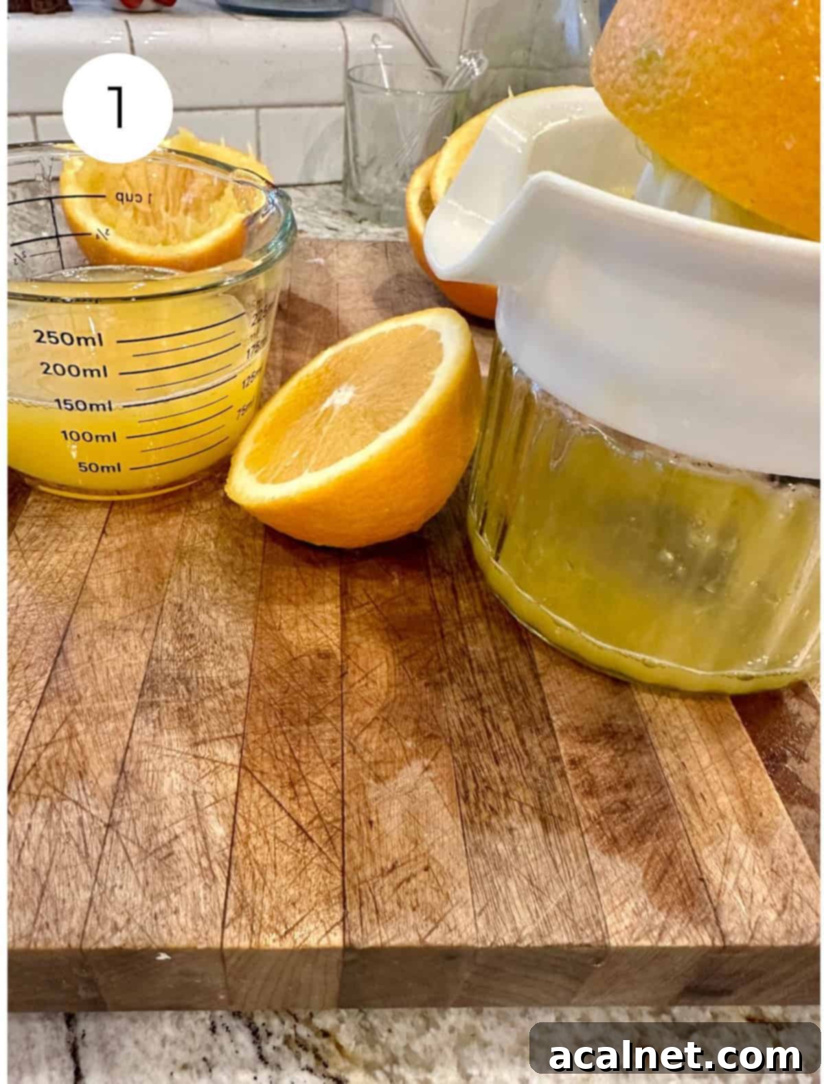 Oranges sliced in half with orange juice in a container on a cutting board.