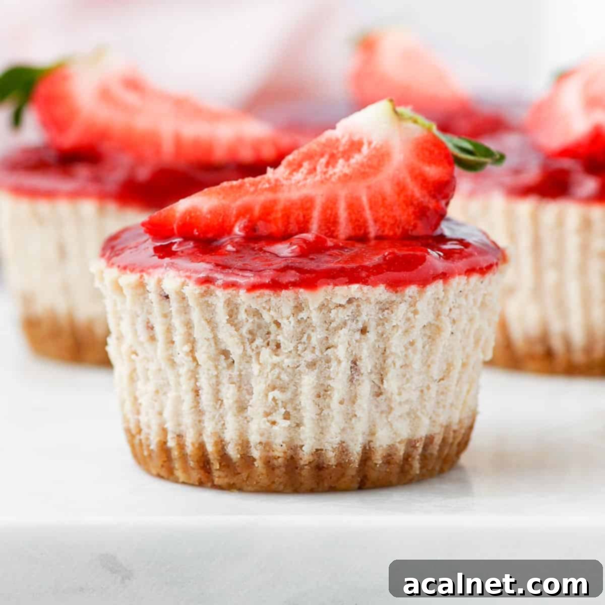 Close up on a mini strawberry cheesecake, perfectly portioned and ready to be enjoyed, placed on a grey serving tray.