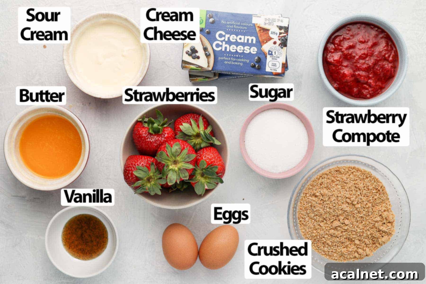 Selection of fresh and pantry ingredients on a white surface for making mini strawberry cheesecakes.