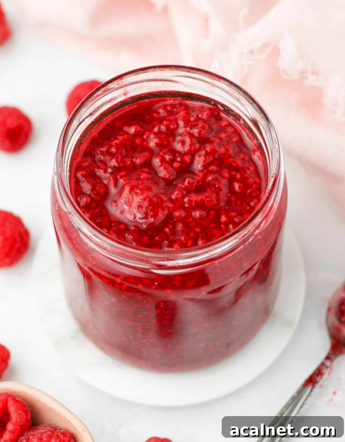 Easy 3 Ingredient Raspberry Compote 7 Cooled down raspberry compote stored neatly in a clear glass jar, showcasing its rich color and texture.