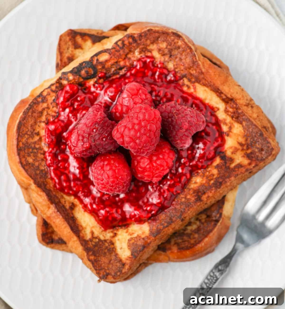 Easy 3 Ingredient Raspberry Compote 8 Fresh raspberries and raspberry compote elegantly drizzled over a stack of golden French toast, showcasing a delightful breakfast or dessert option.