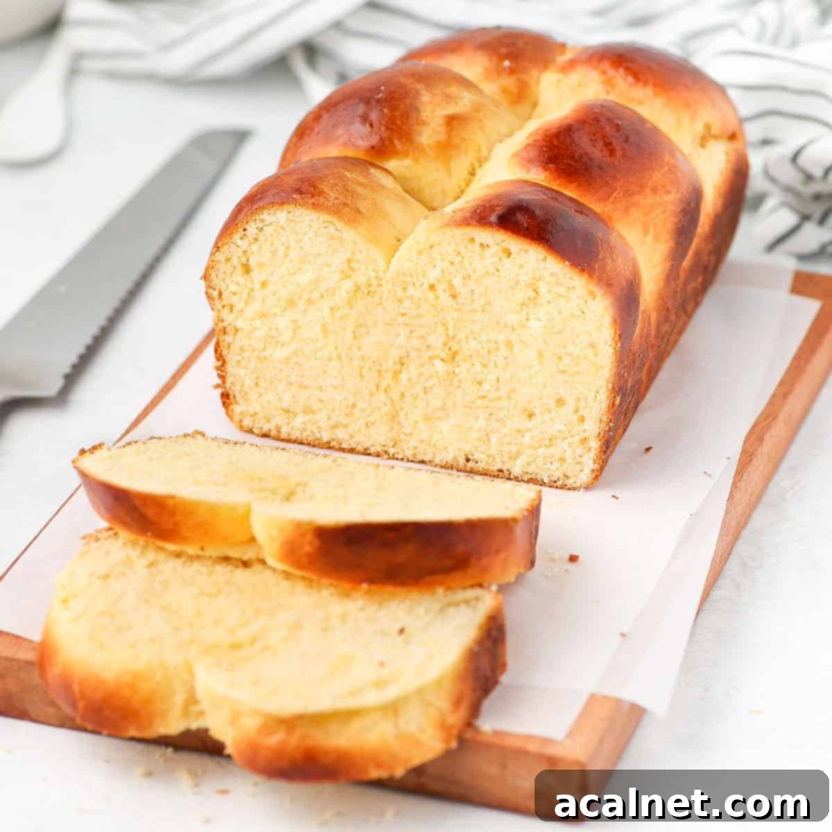 Brioche loaf sliced on a wooden board, showcasing its fluffy texture.