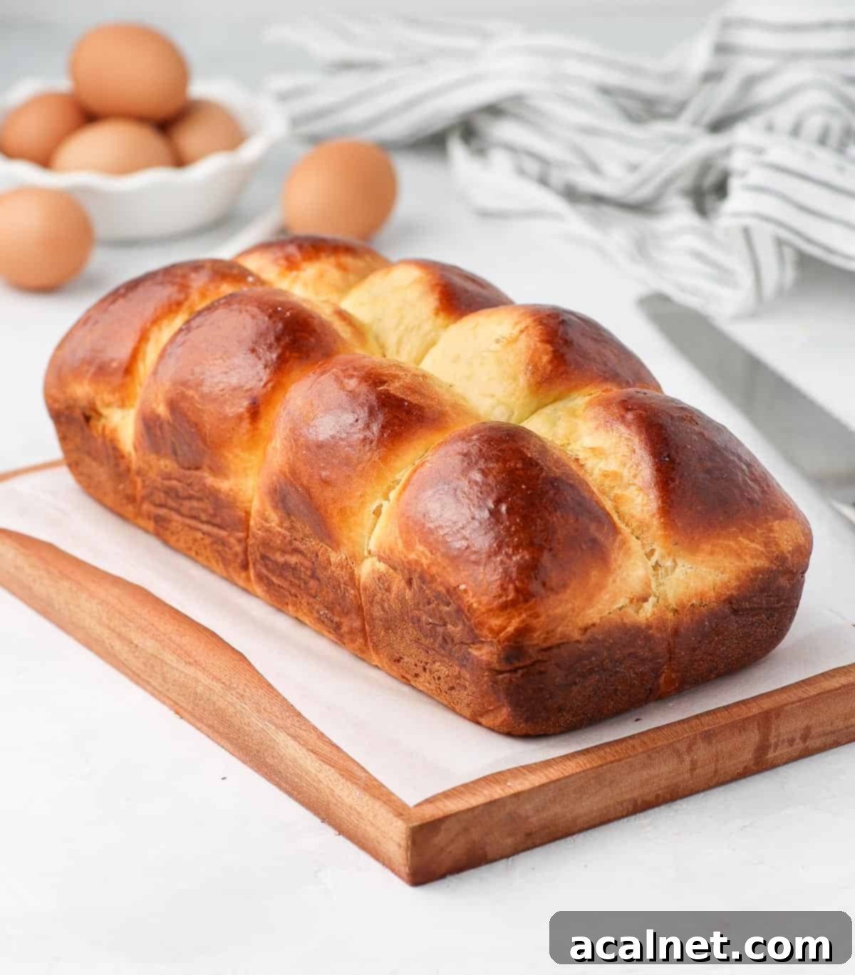 A freshly baked brioche loaf resting on a wooden board, showcasing its golden crust.