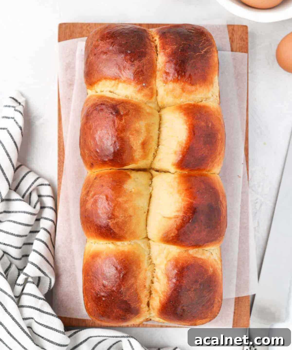 A baked brioche loaf, viewed from above, resting on a rustic wooden board.