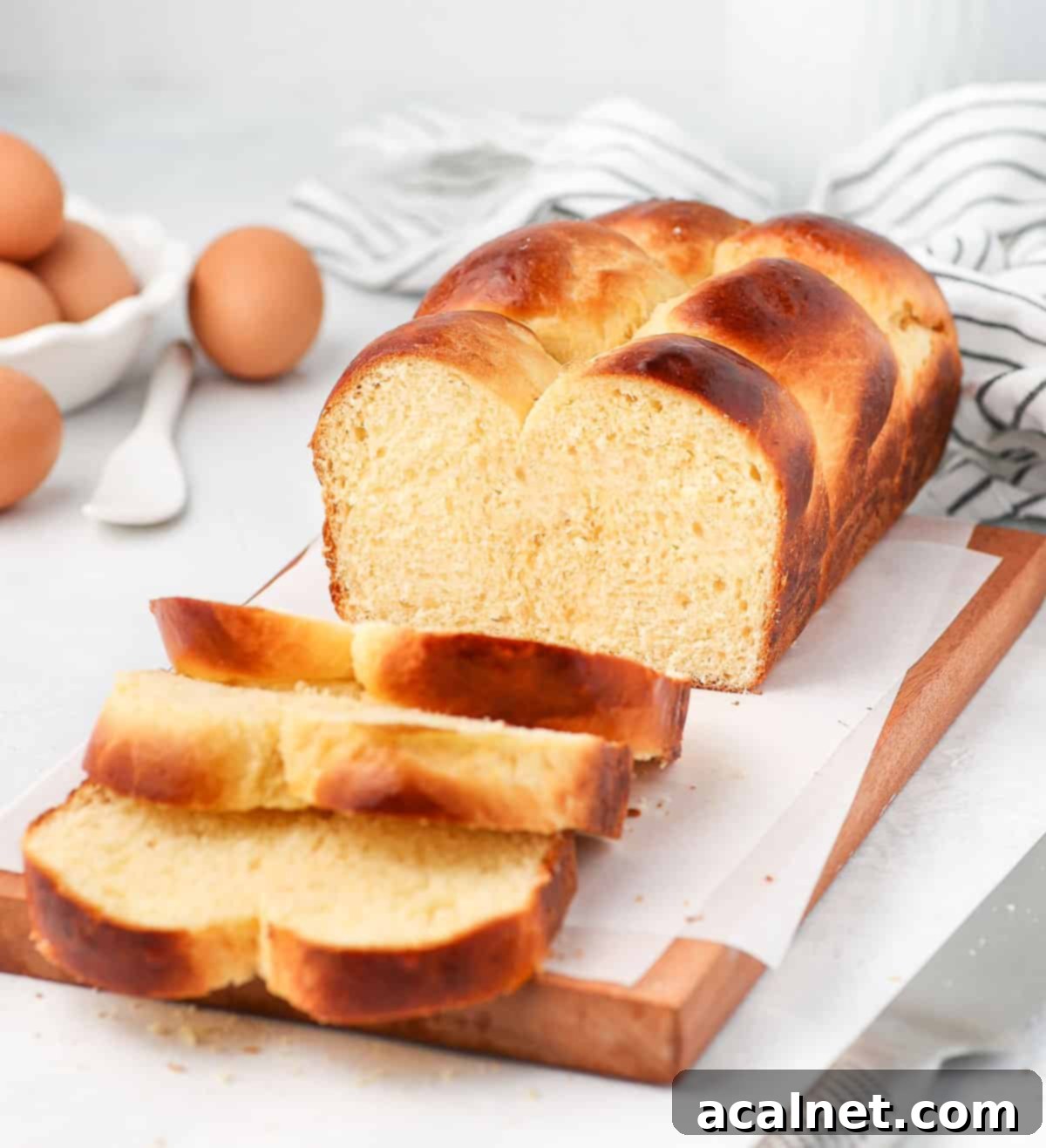 A brioche loaf on a cutting board with three slices already cut, revealing the soft interior.