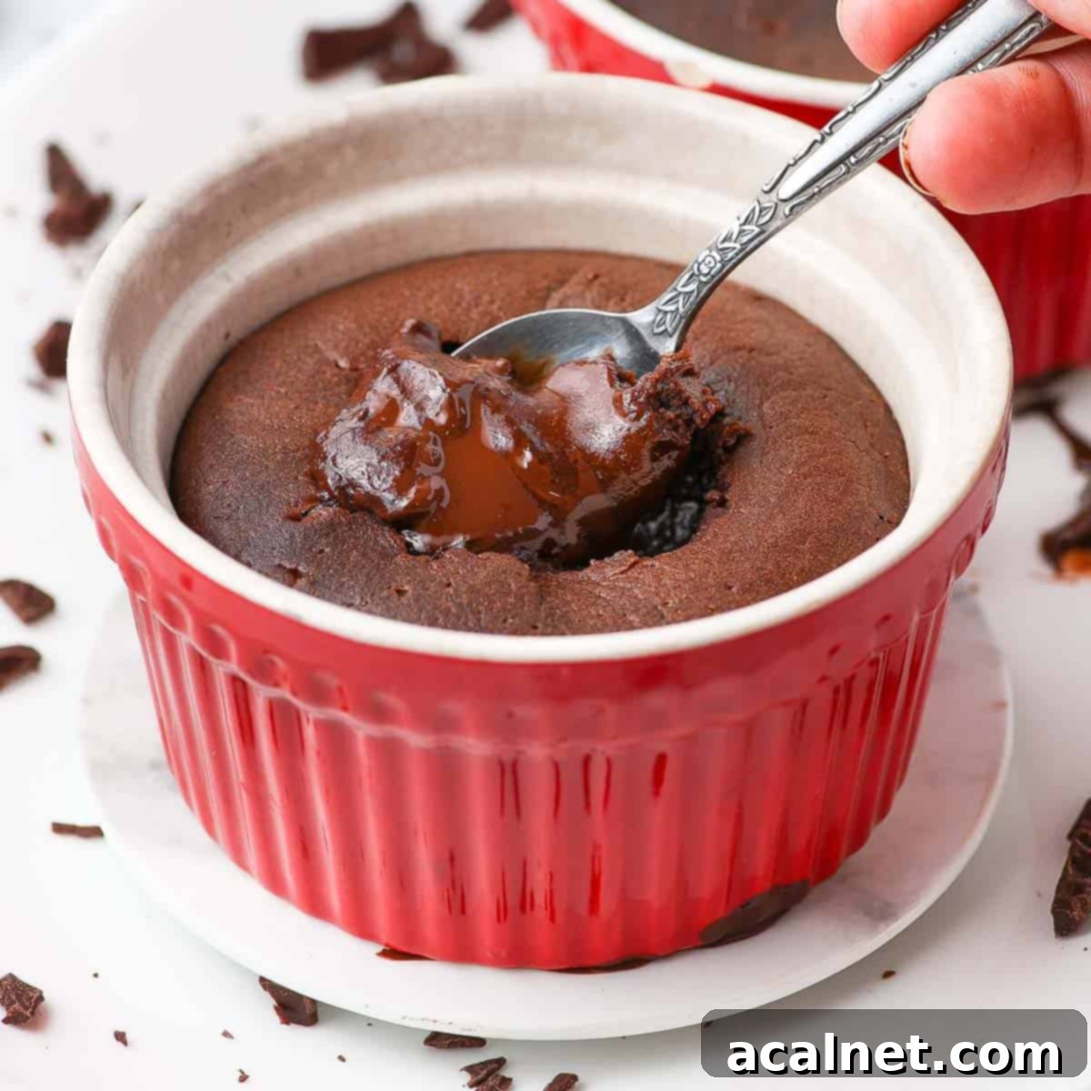 A spoon dipping into a warm chocolate fondant cake, revealing its molten, gooey center. The rich, dark chocolate interior is inviting and decadent, served in a ramekin.