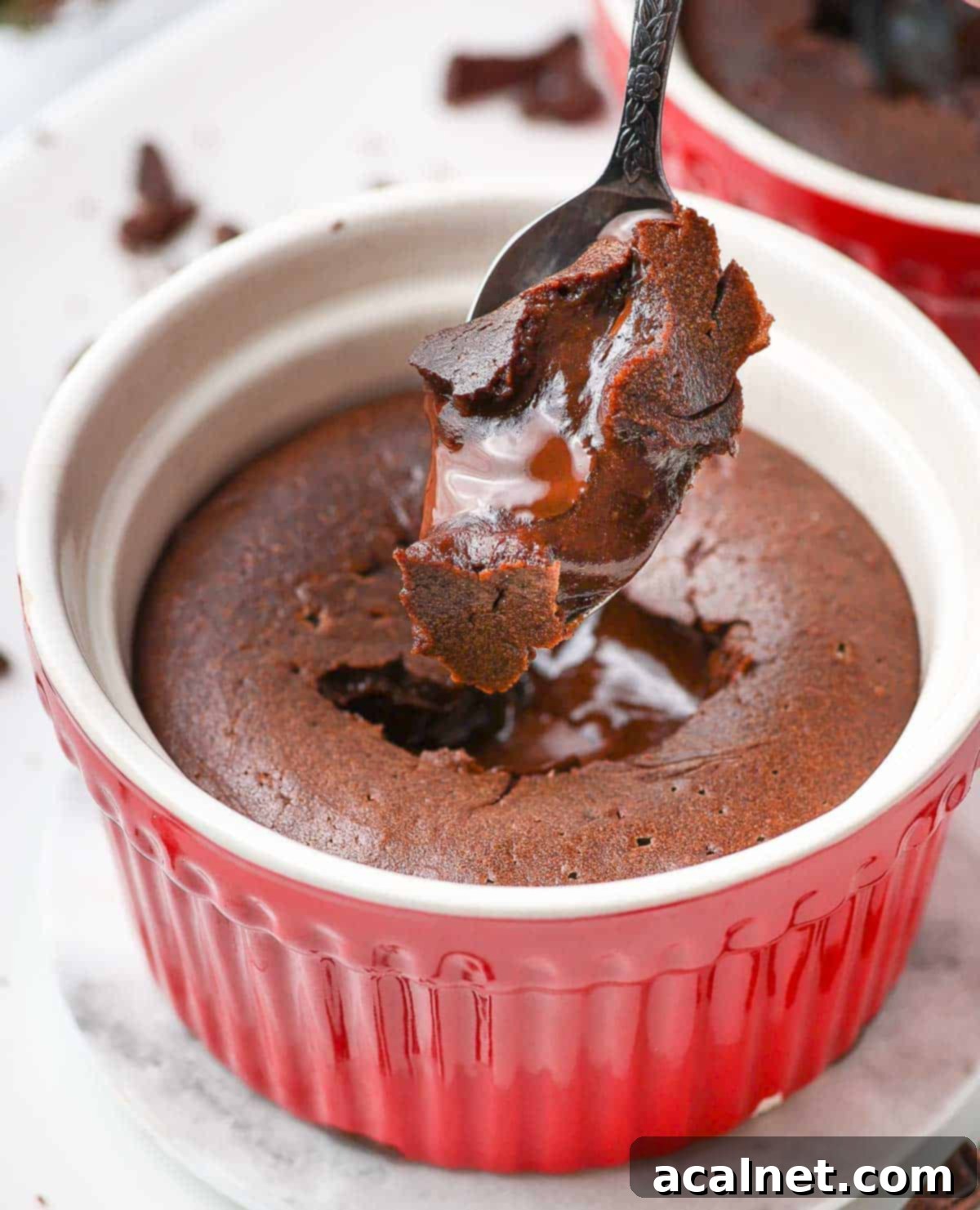 Molten chocolate batter dripping from a spoon, showcasing its rich, thick, and luxurious texture, ready to be poured into ramekins.