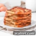 Brioche french toasts stacked on a white plate over a beige napkin.