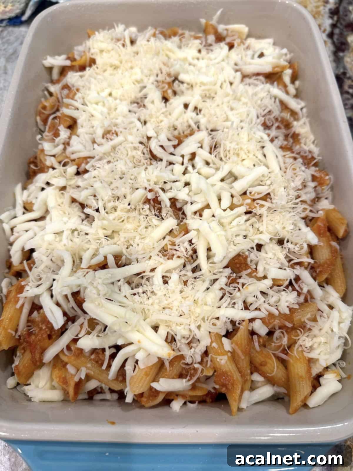 Unbaked lazy lasagna in a baking dish with mozzarella and parmesan cheese on top, ready for baking.