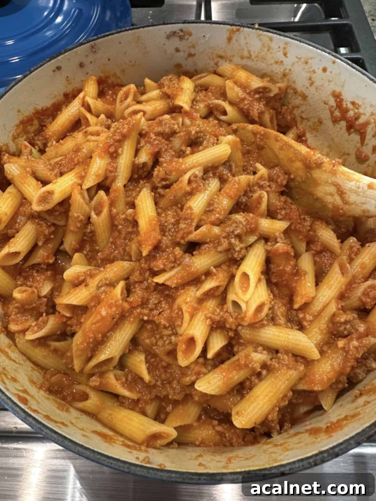 Pasta, meat, and marinara sauce for lazy lasagna being combined in a large pot on the stove.
