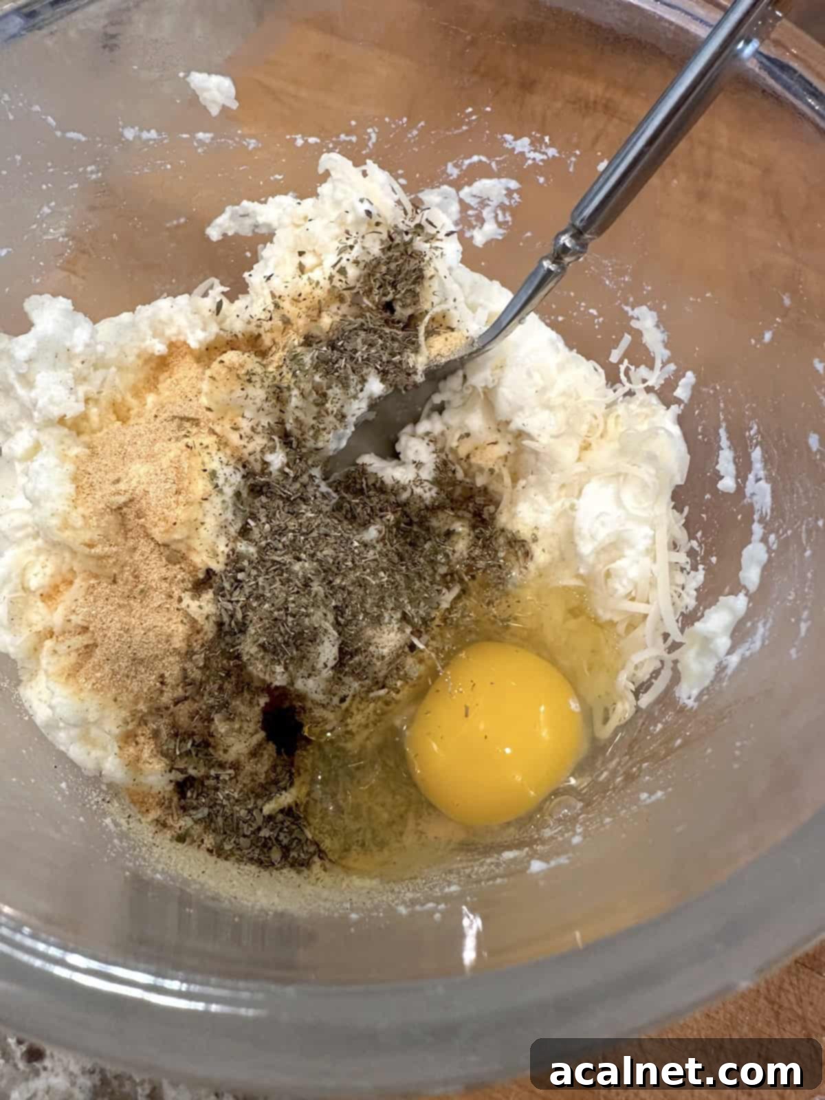 Ricotta cheese filling with egg, Parmesan cheese, garlic powder, salt, and Italian seasoning in a small bowl.