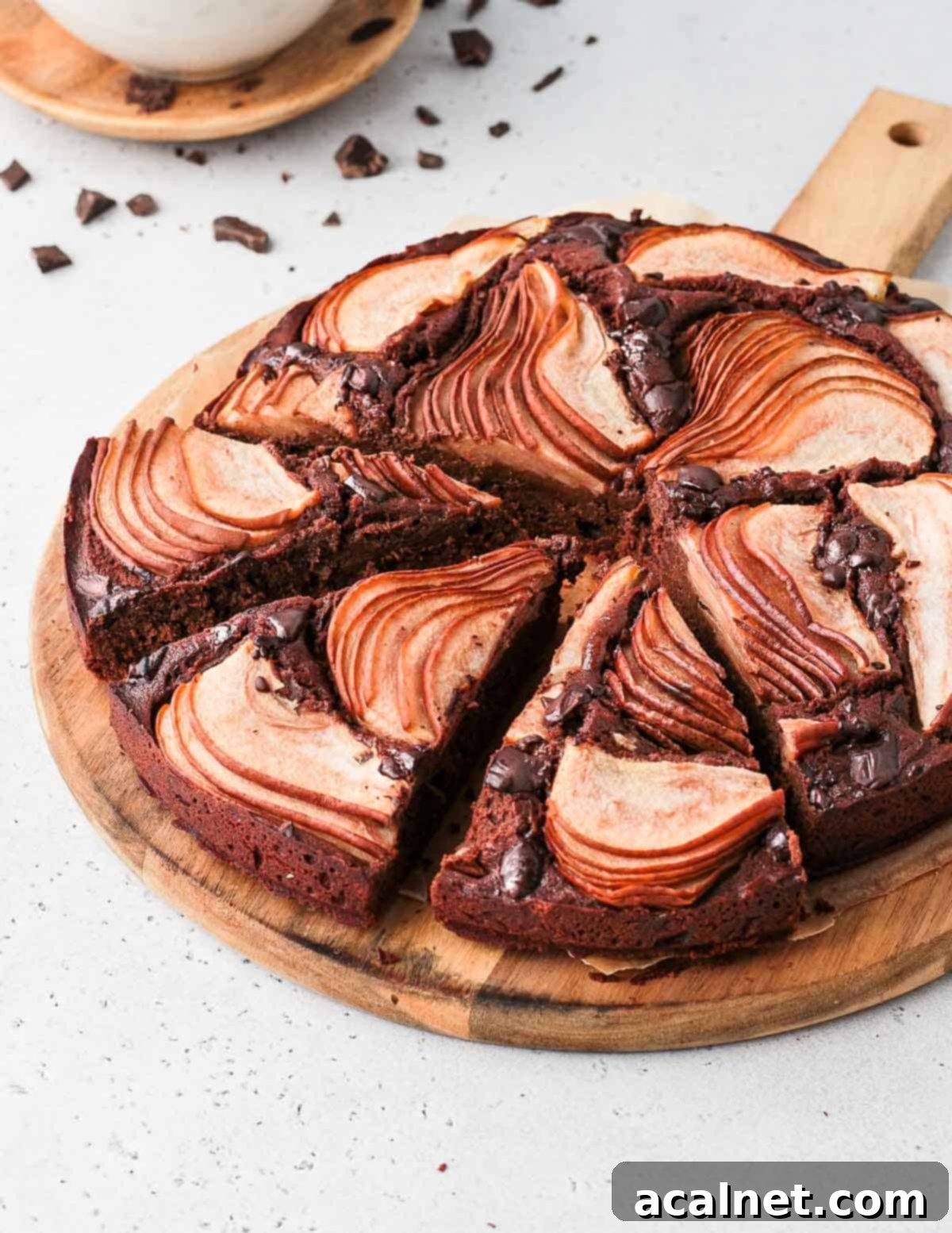 A close-up of a Chocolate Pear Cake on a white marble surface with three slices already cut and removed, showing the cake's interior.