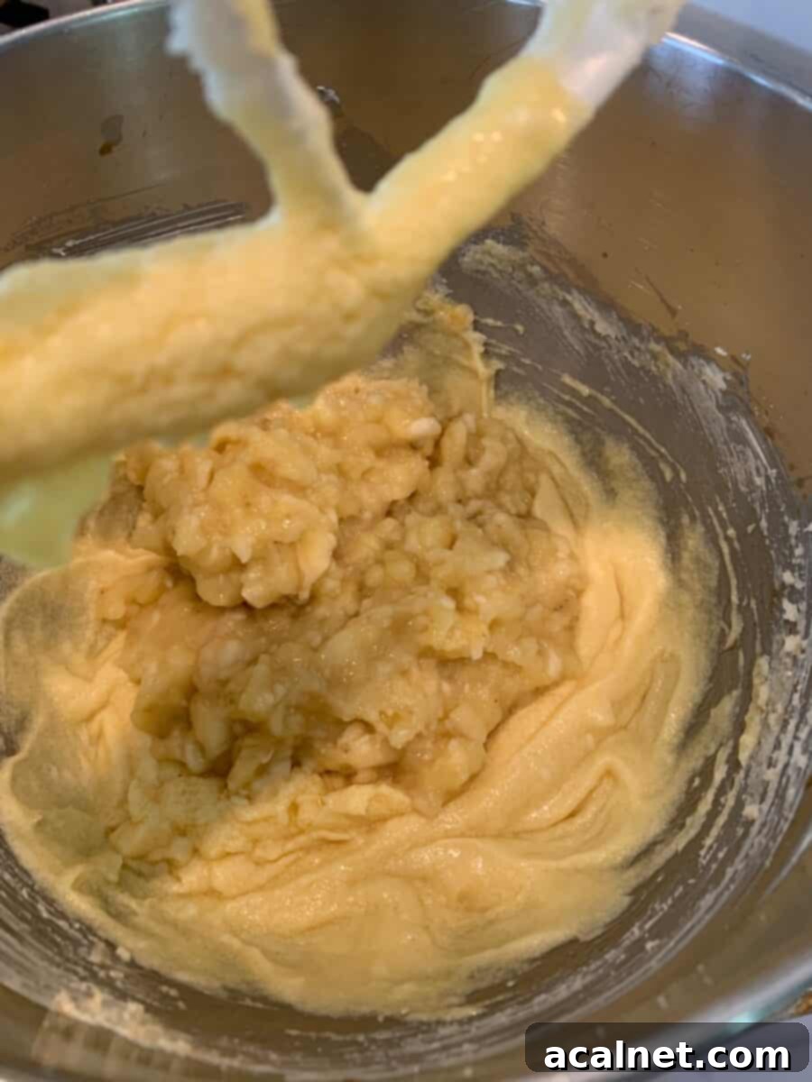 Mashed bananas and other wet ingredients in a mixing bowl.