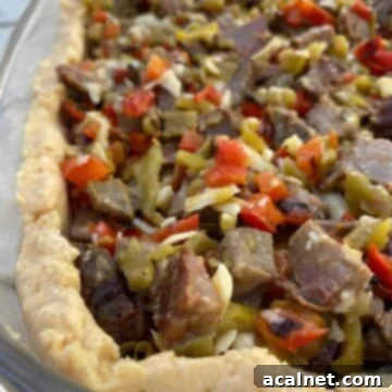 Hearty diced beef with vibrant red peppers and green salsa baked into a golden tamale crust, all presented in a large glass baking dish.