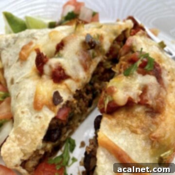 A large, perfectly baked beef and cheese burrito cut in half on a plate, revealing its delicious filling.