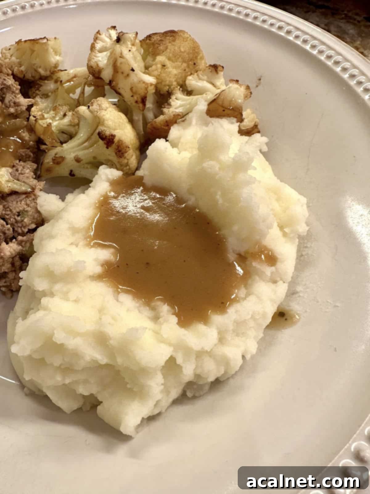 Rich gravy drizzled over creamy mashed potatoes on a plate, ready to be served.