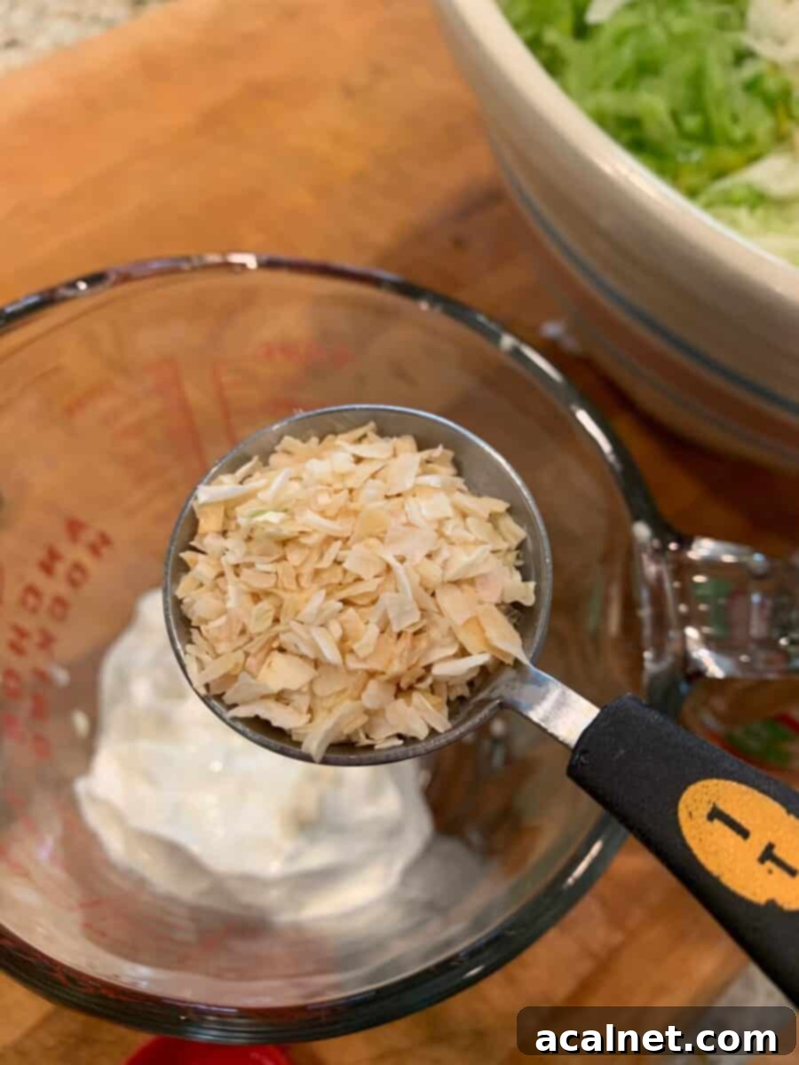 Dried onion flakes and other dressing ingredients in separate small bowls, showcasing the components that make the cole slaw dressing flavorful.