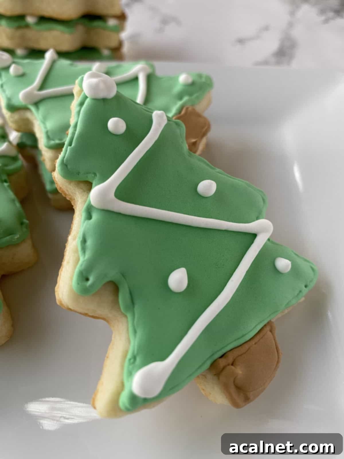 Sugar cookies shaped like Christmas trees on a plate.