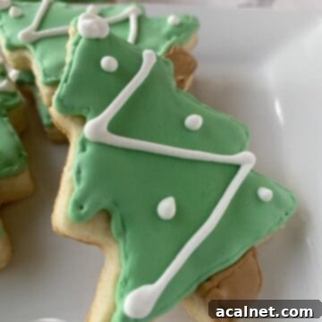 Sugar cookies shaped like Christmas trees on a plate.