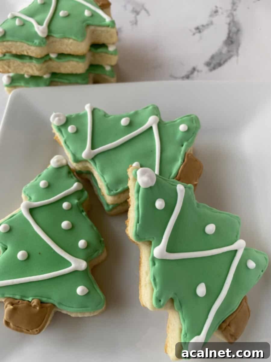 Sugar cookies shaped like Christmas trees stacked and arranged on a plate.