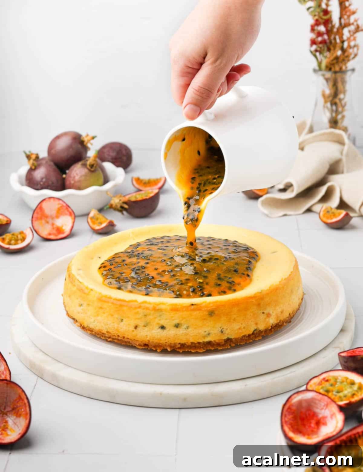 Effortless Passion Fruit Coulis 7 Pouring the passion fruit sauce over a cheesecake, highlighting its smooth yet textured consistency.