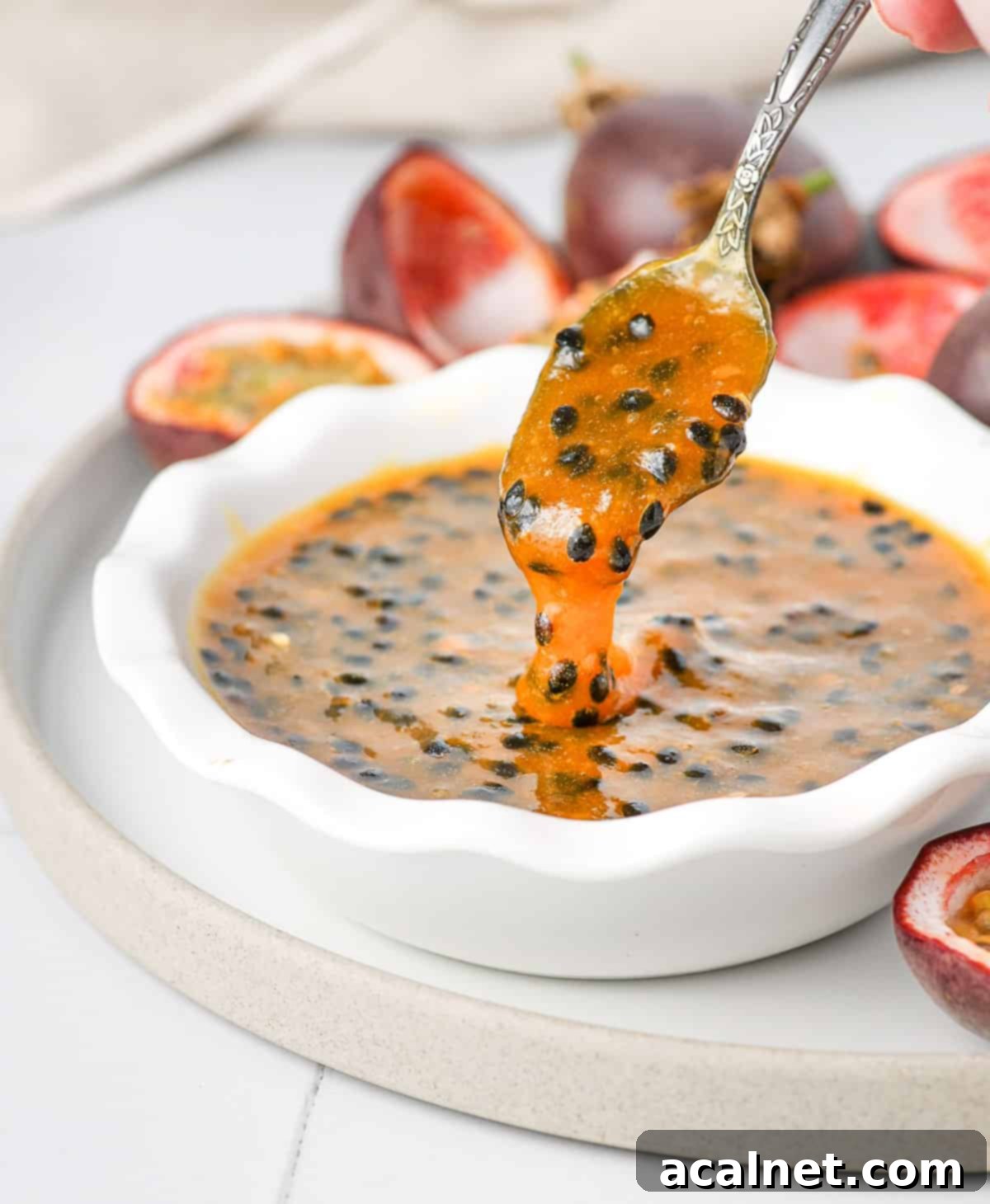 Effortless Passion Fruit Coulis 8 Pouring the coulis from a spoon into the bowl, showing its texture.