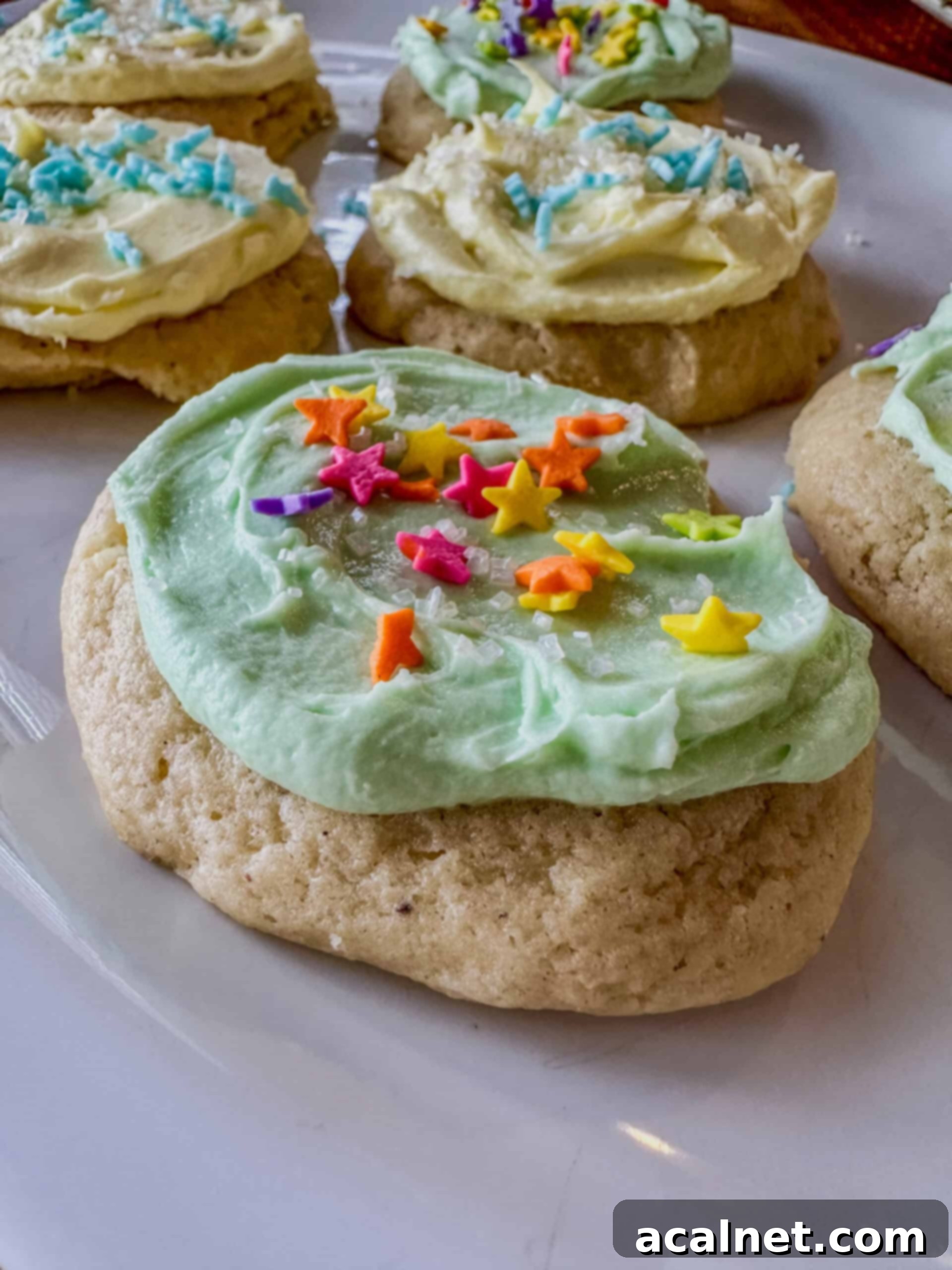 A cookie covered with frosting and sprinkles on a plate.