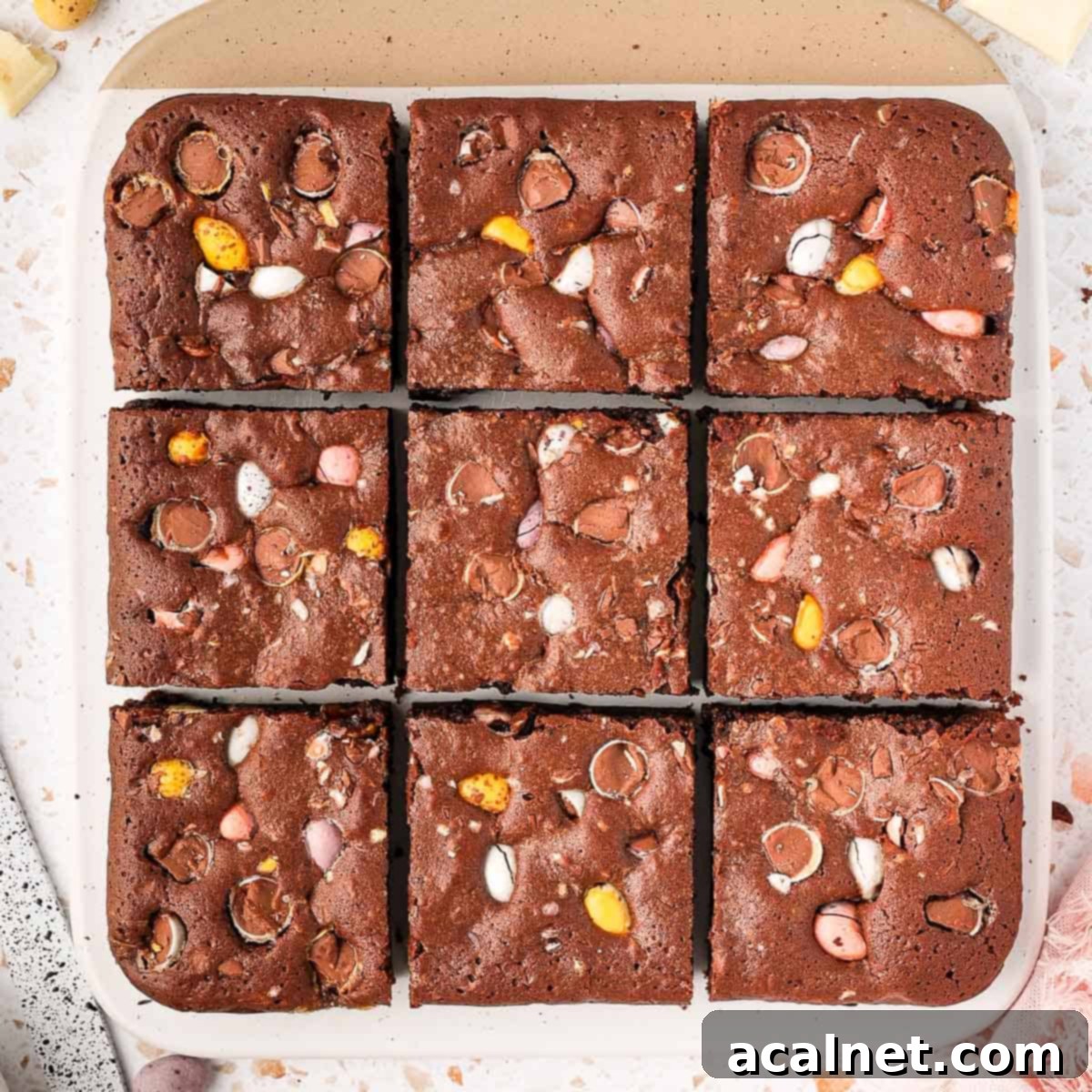 Easter brownies on a white and beige board seen from above, cut into 9 pieces.
