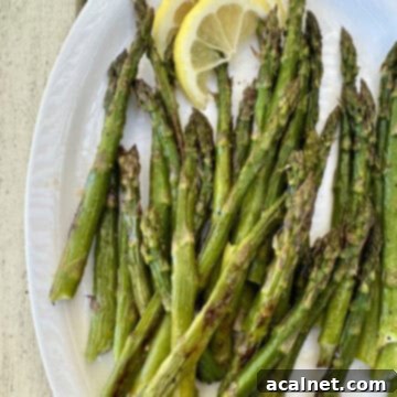 Pan roasted asparagus on a plate with lemon slices.