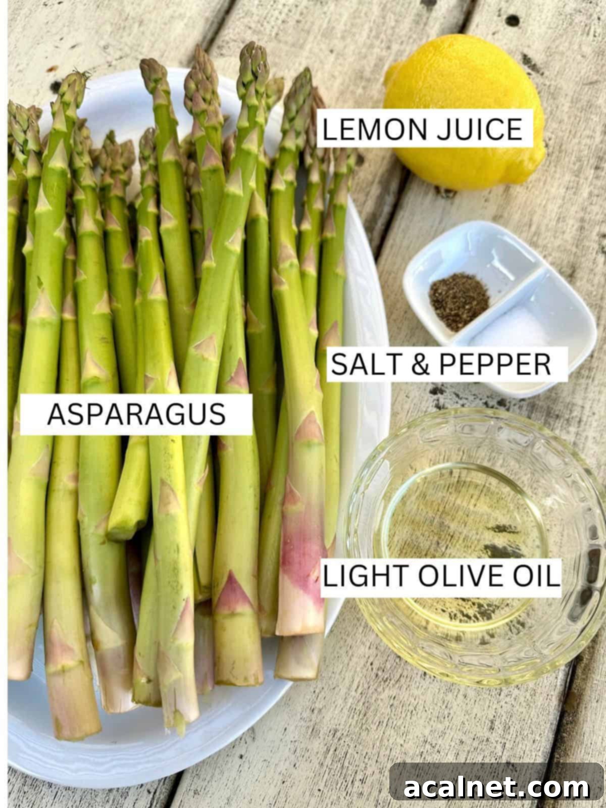 A flat lay of fresh ingredients for pan-roasted asparagus, including bright green asparagus spears, a whole lemon, and a bottle of olive oil, neatly arranged on a rustic wooden table.