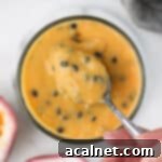 Picking up some vibrant passion fruit curd from a jar with a spoon.