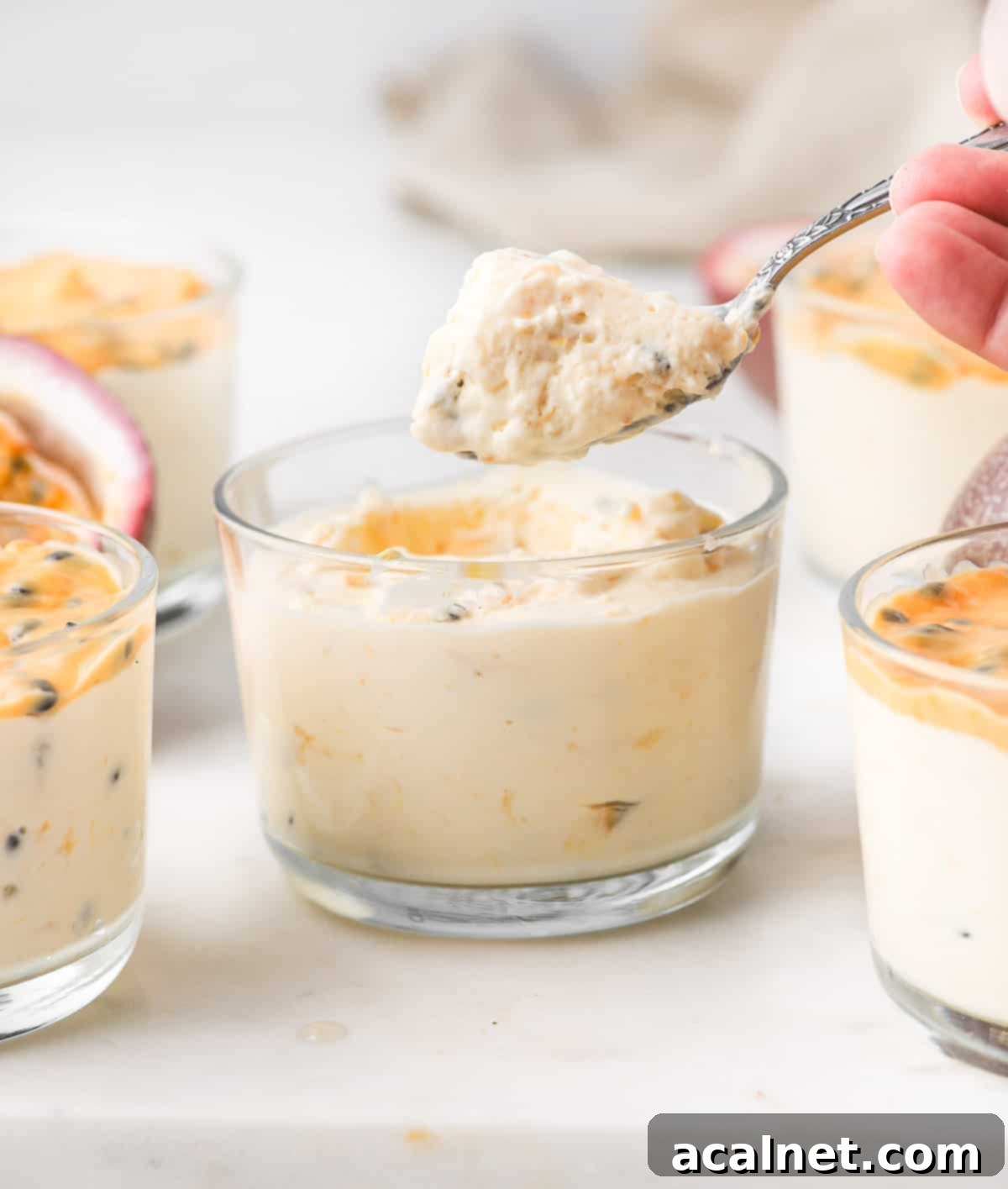Simple Passion Fruit Cloud 9 A spoonful of creamy passion fruit mousse being lifted from a serving cup, showcasing its light, airy texture and the tiny, crunchy passion fruit seeds embedded within the tropical dessert.