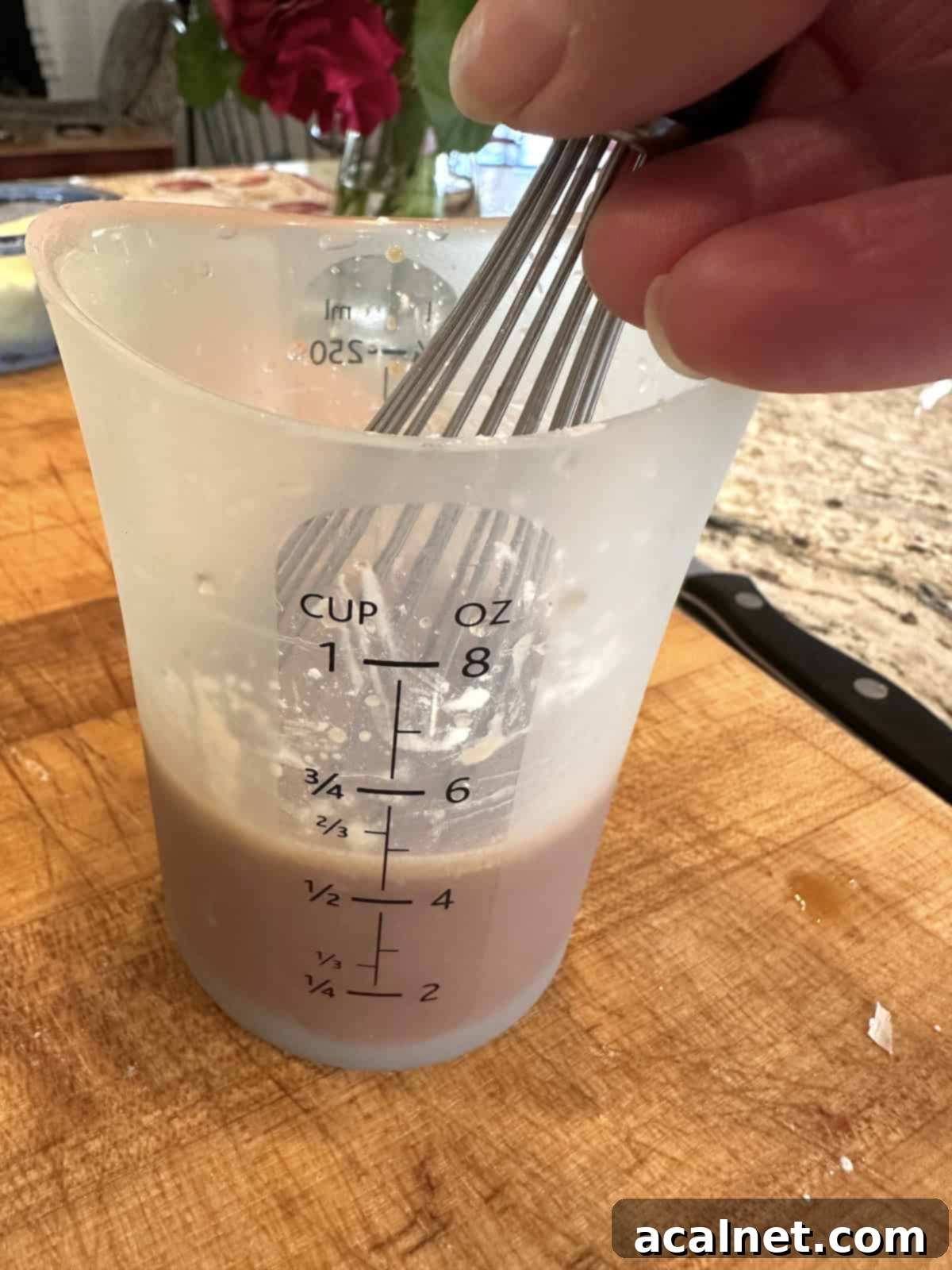 Sauce ingredients for spring roll in a bowl in a measuring cup with a whisk on a cutting board, prepared ahead of time.