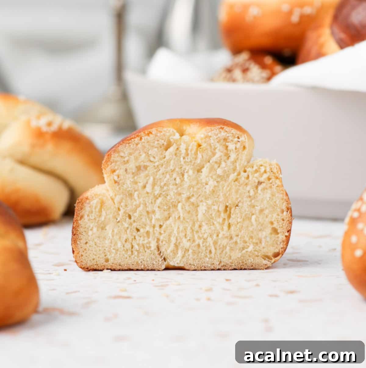 A mini challah roll sliced in half, revealing its incredibly soft, airy, and fluffy interior crumb.