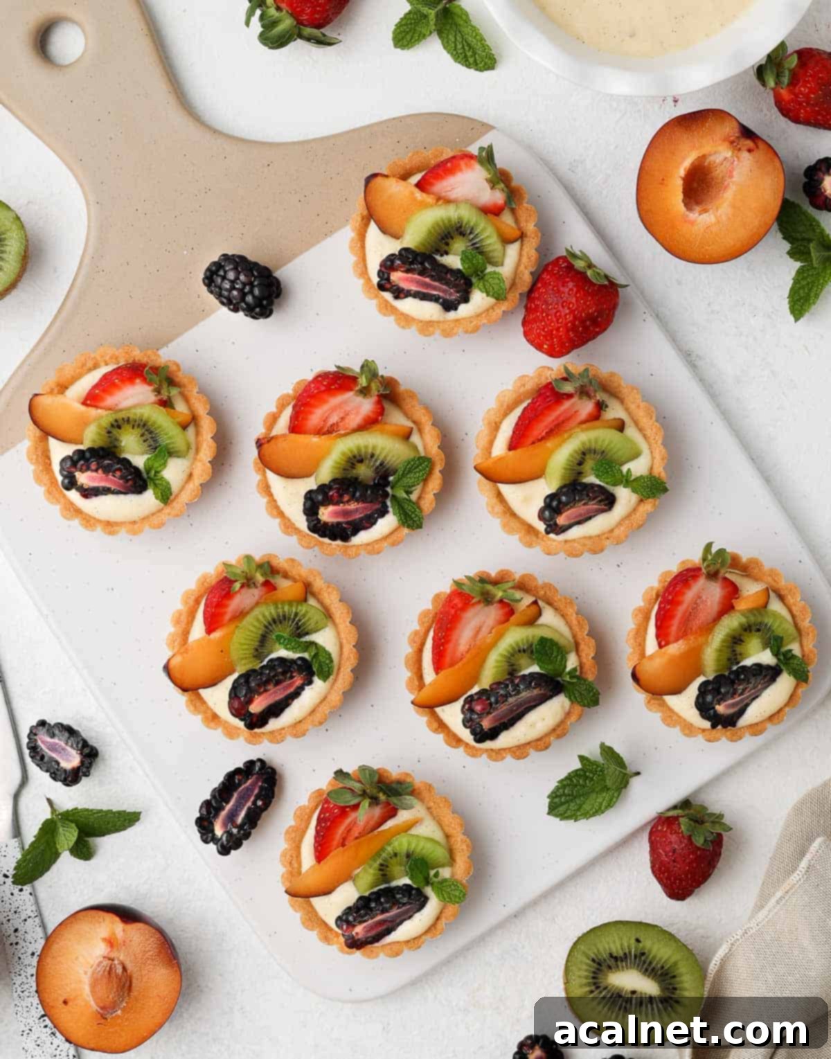 Petite Fruit & Cream Tarts 8 Tartlets on a serving board seen from above, displaying a variety of colorful fruits.