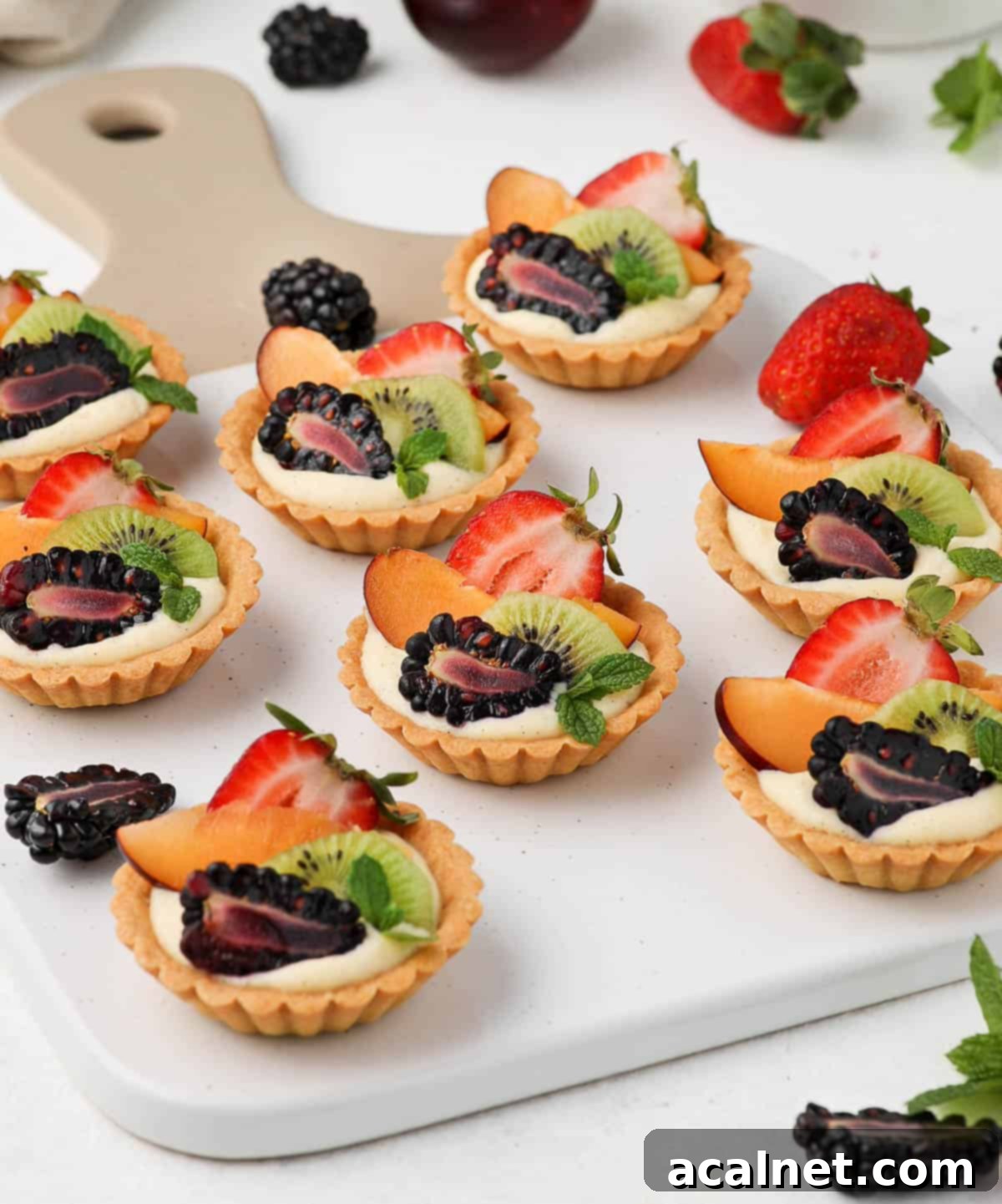 Petite Fruit & Cream Tarts 9 Serving the tarts on a white and beige board, showcasing their elegant presentation.