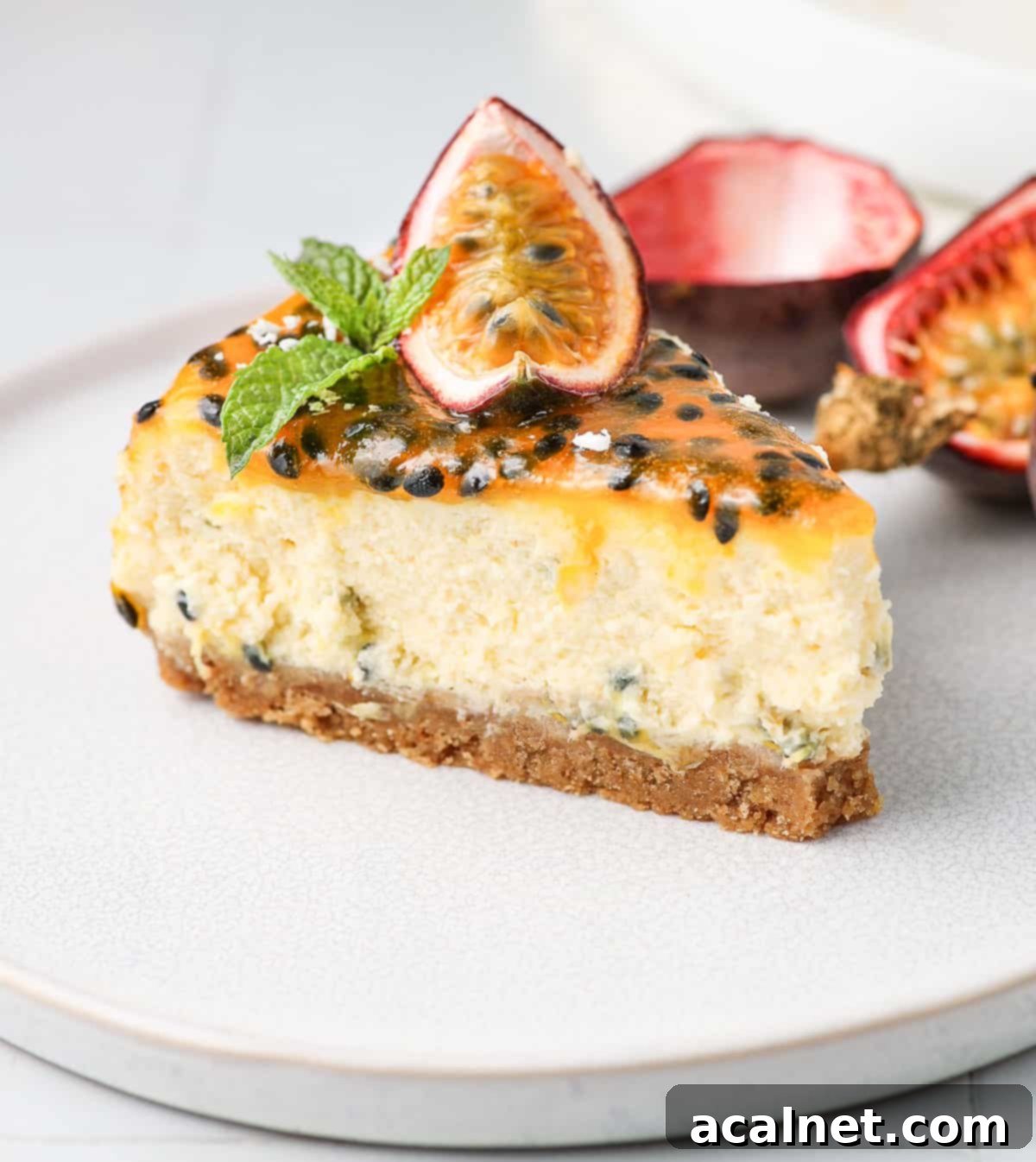 A single slice of baked passion fruit cheesecake on a small white plate, showing the creamy texture and biscuit crust, garnished with fresh passion fruit.