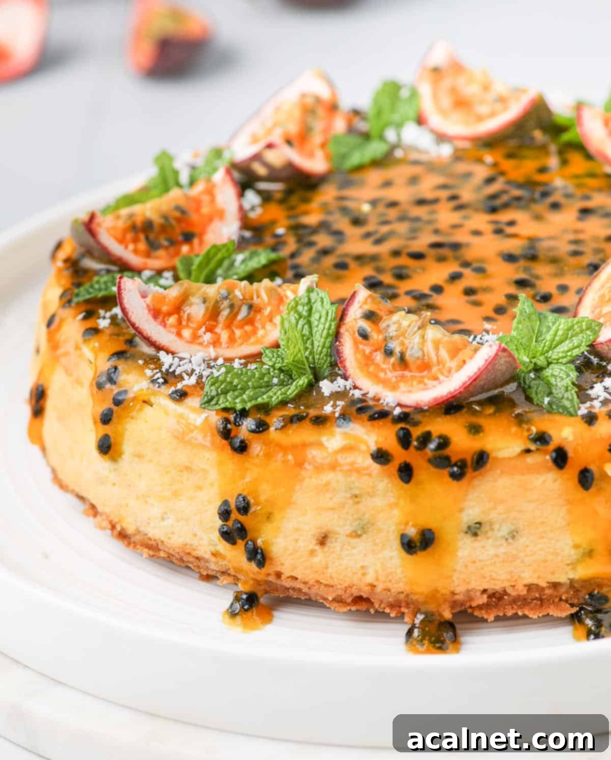 Close up on the side of a passion fruit cheesecake, showing the layers of biscuit crust, creamy filling, and the coulis gently dripping down the sides.