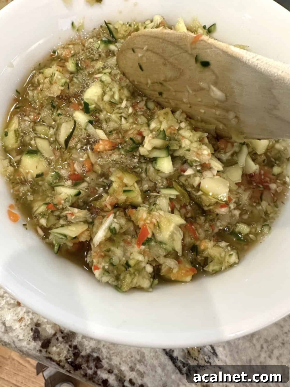 A spoon stirring pickle de gallo in a bowl, ensuring all ingredients are well combined.