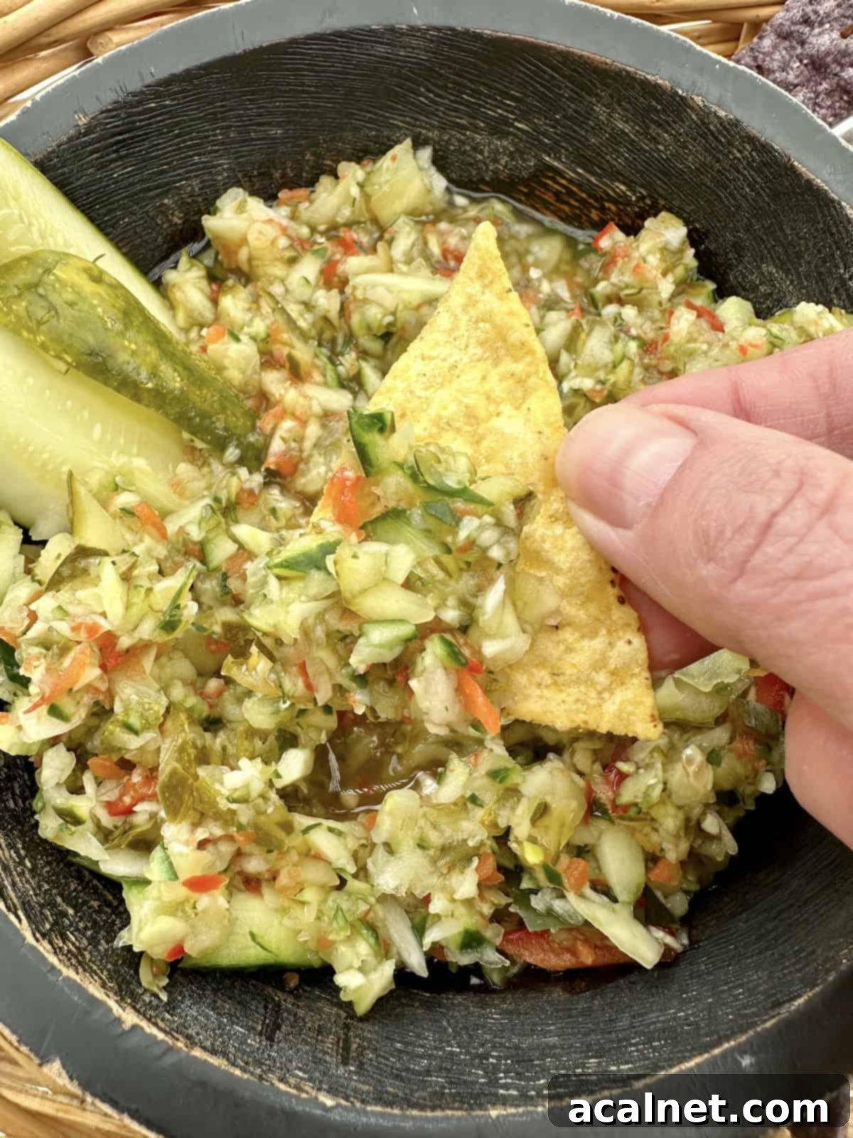 A tortilla chip scooping up a generous portion of Pickle de Gallo, ready to be enjoyed.