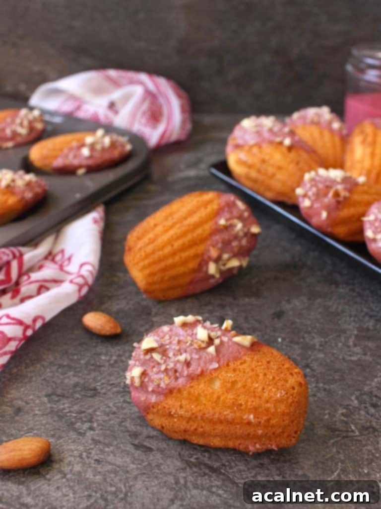 One madeleine on its side on a grey surface with almonds.