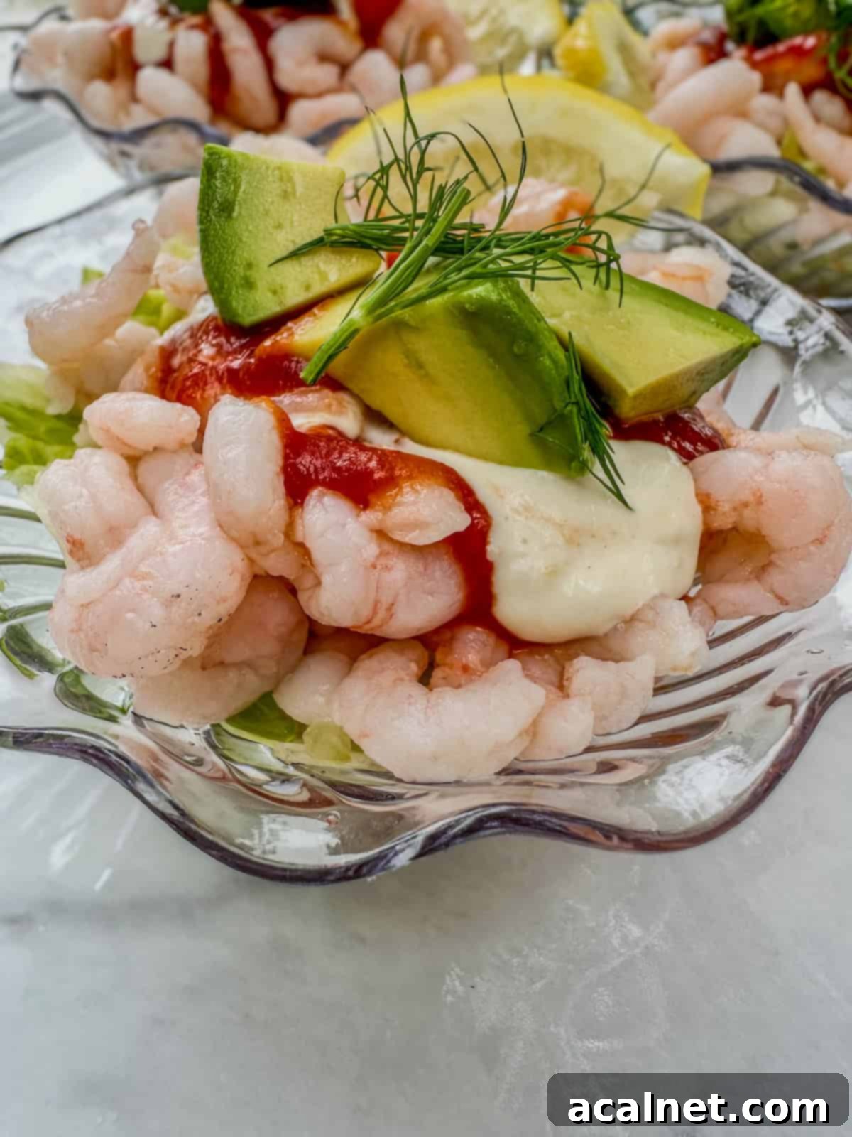 Shrimp Cocktail Shooters 2 Shrimp cocktail cups with fresh dill and sliced avocado on top.