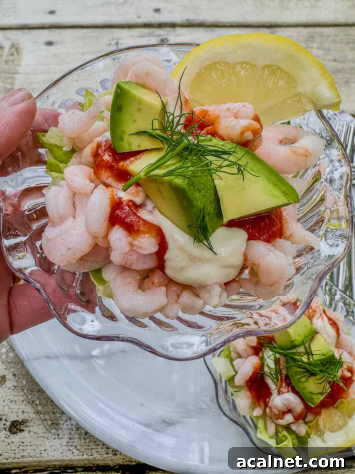 Shrimp Cocktail Shooters 9 A hand holding a serving of shrimp cocktail in a cup.