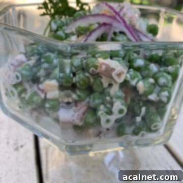 A delightful English Pea Salad in a clear glass serving bowl, perfectly chilled and ready to be served on an inviting outdoor table.