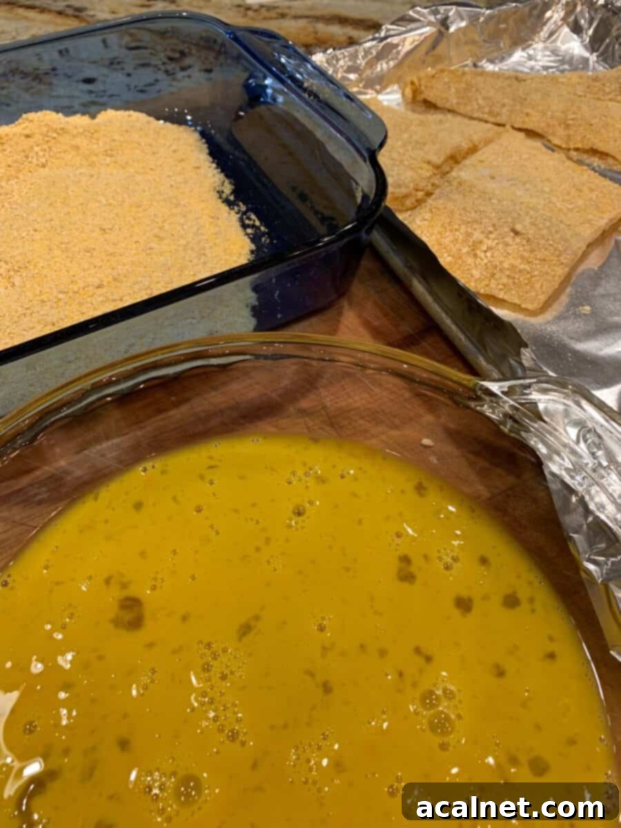 Ingredients laid out: whisked eggs in a bowl, a pile of seasoned cracker crumbs, and pieces of cod fillet.