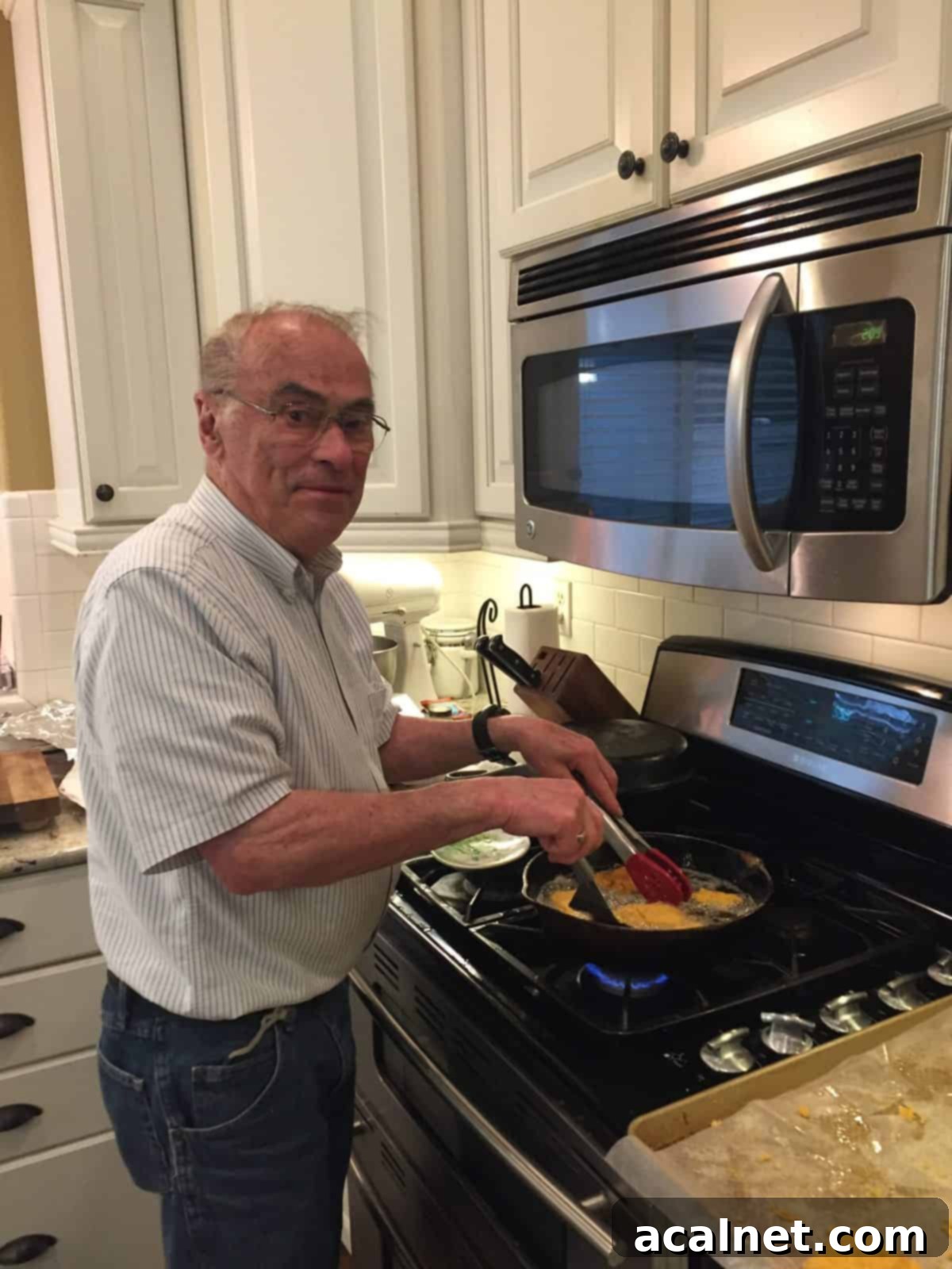 Melinda's dad proudly frying cod in a well-loved cast iron skillet on the stove, embodying generations of cooking tradition.