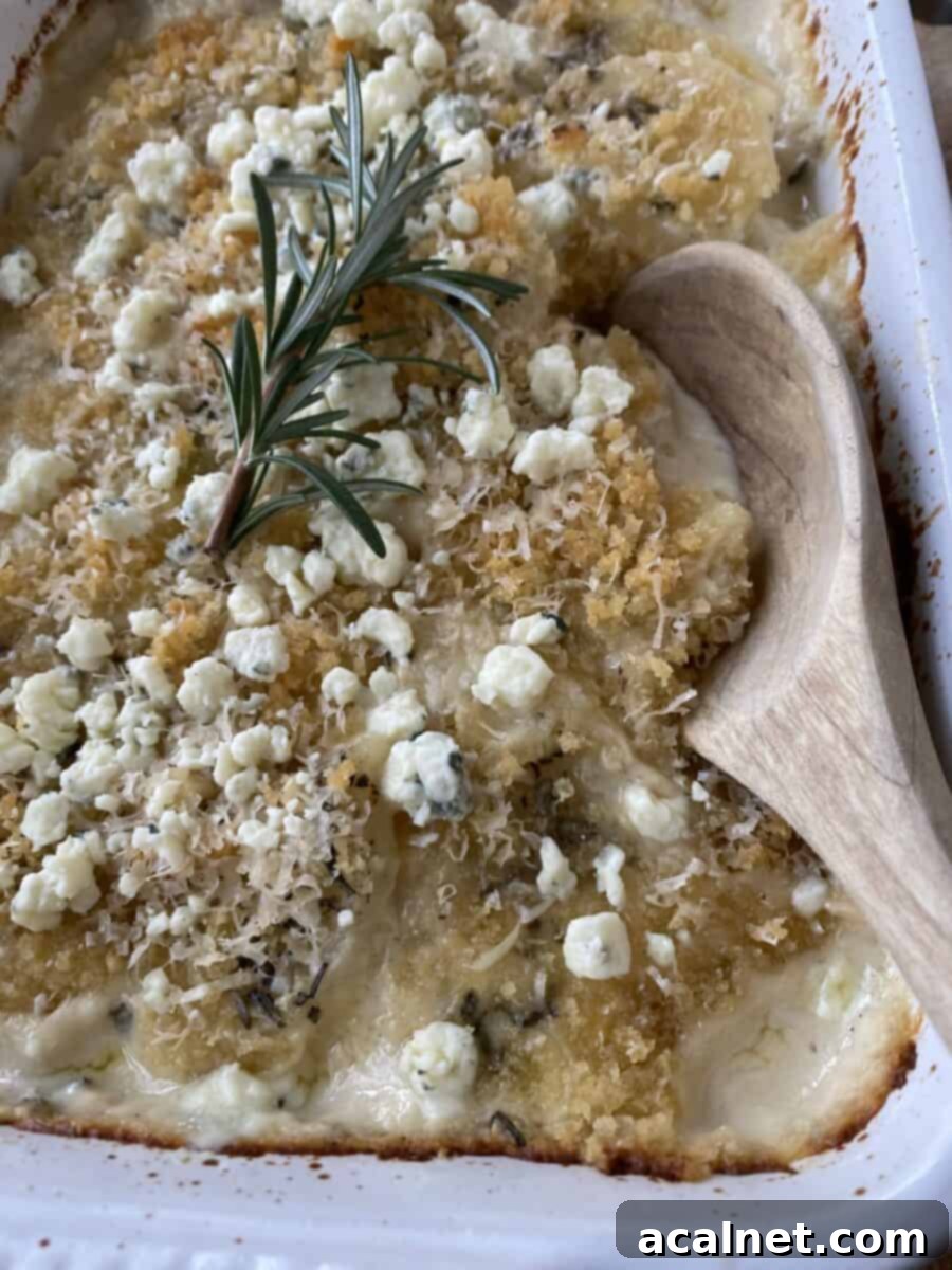 Blue Cheese and Rosemary Scalloped Potatoes baked, with a wooden spoon in the dish for serving.
