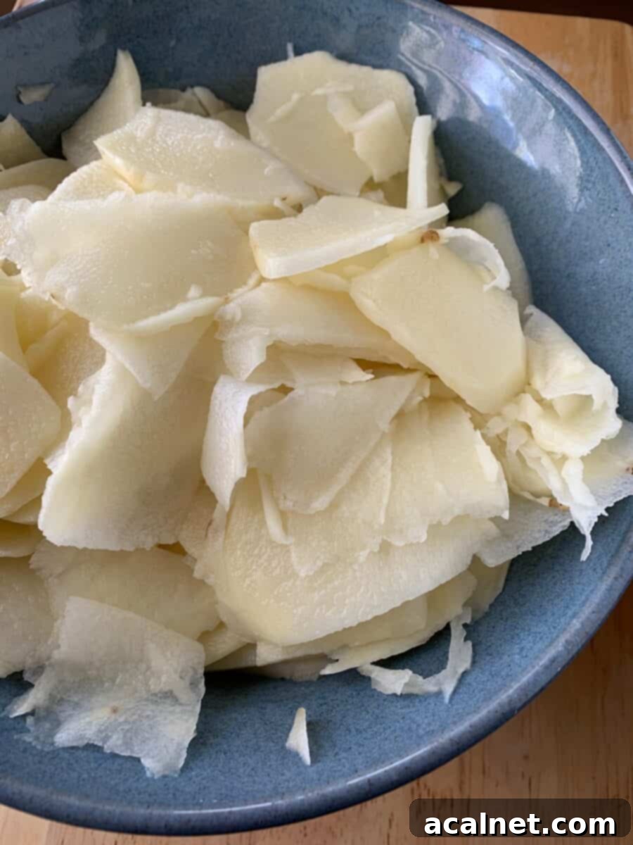 Sliced, raw potatoes in a bowl. 